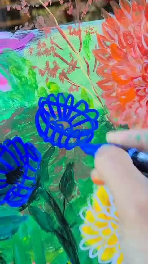 A butterfly outlined in bright blue paint pen on glass, over a painted bank of orange dahlias.